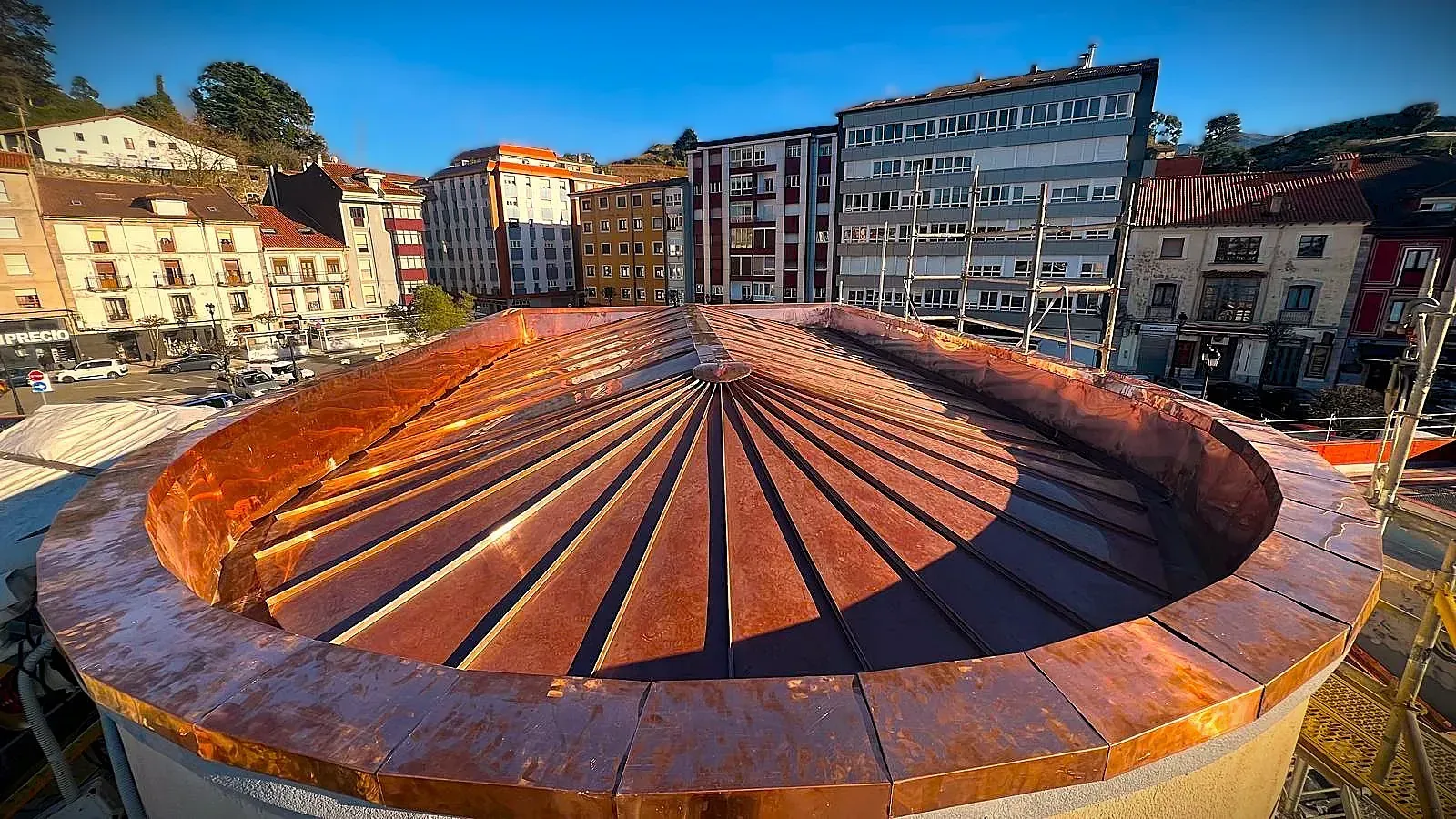Una estructura circular con techo de cobre se encuentra en el medio de una ciudad.