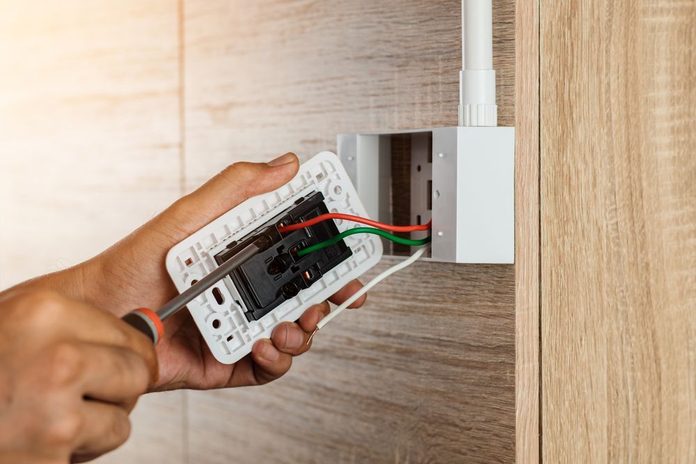 Una persona está arreglando un tomacorriente eléctrico con un destornillador.