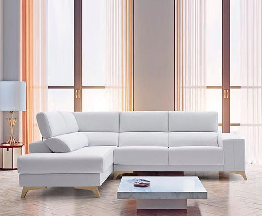 Sofá seccional blanco en sala de estar moderna con grandes ventanales, patas de madera clara y mesa de centro de mármol.