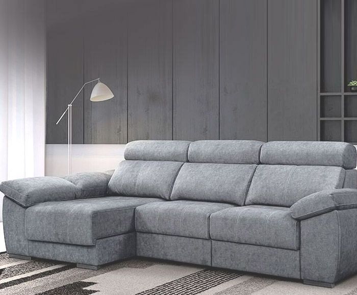Un sofá seccional gris está ubicado en una sala de estar junto a una lámpara.