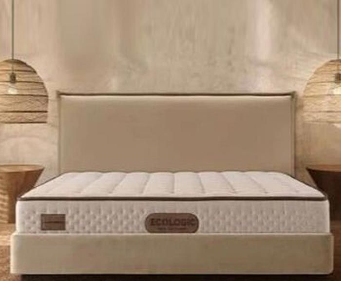 Una cama con un colchón y un cabecero en un dormitorio.