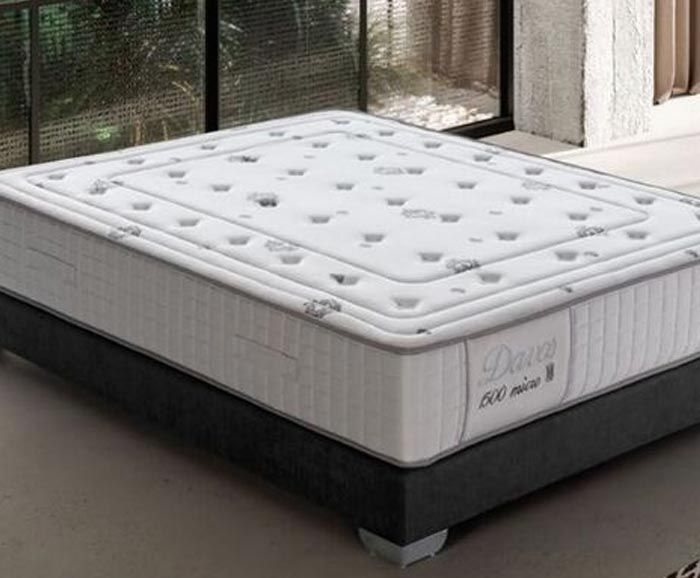 Un colchón blanco está sobre una base negra en un dormitorio.