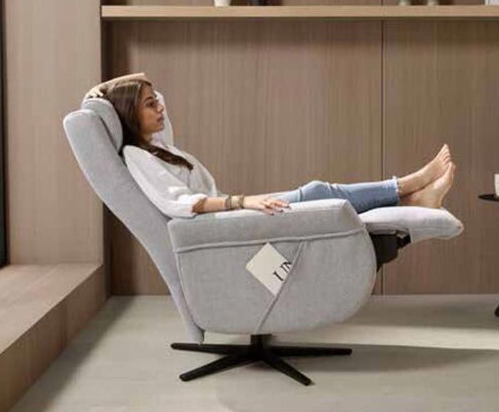 Una mujer está sentada en un sillón reclinable en una sala de estar.