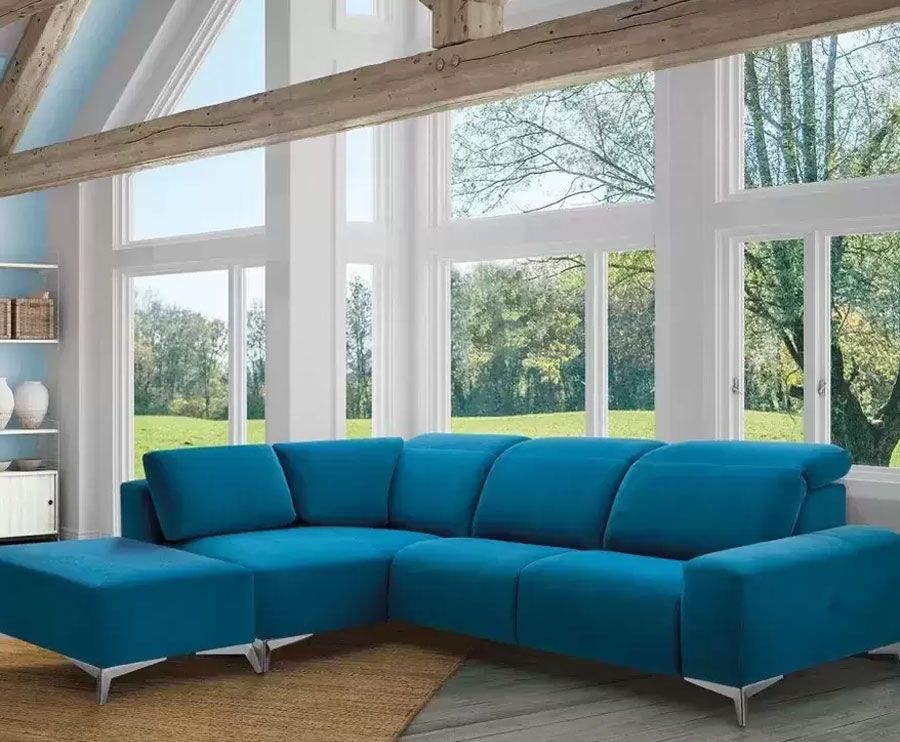 Un sofá seccional azul está en una sala de estar con muchas ventanas.