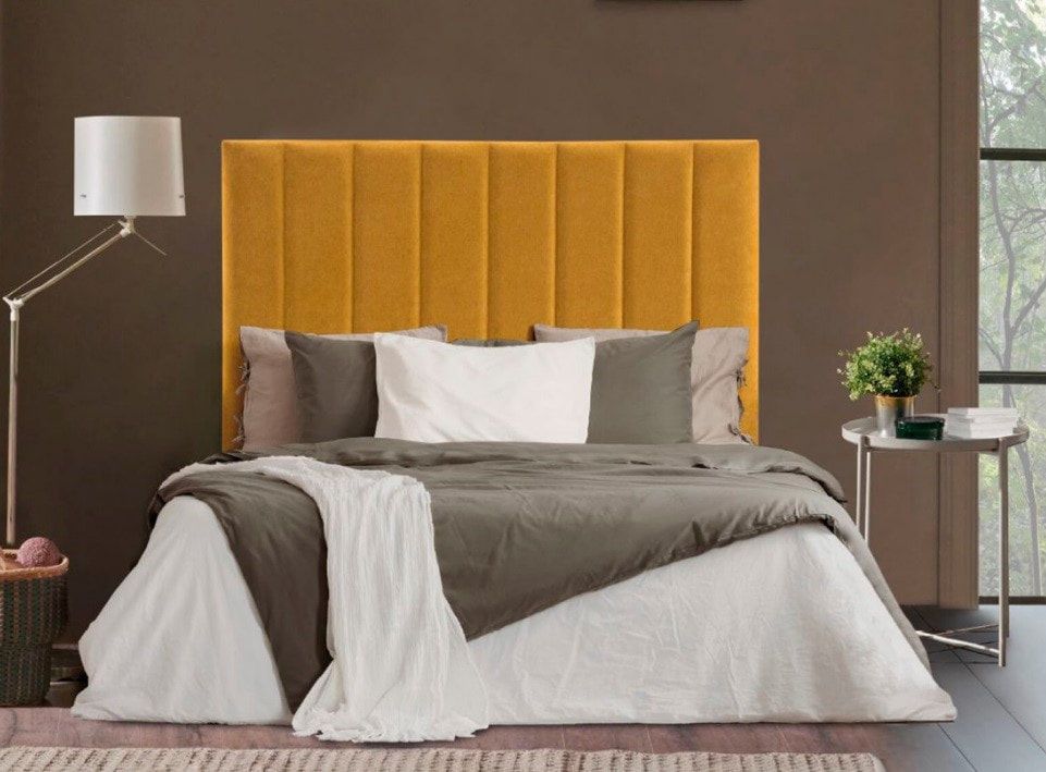 Una cama con cabecera amarilla y sábanas blancas en un dormitorio.