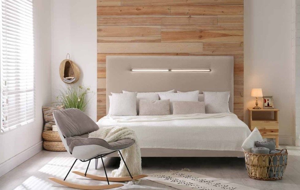 Un dormitorio con una pared de madera detrás de la cama y una mecedora.