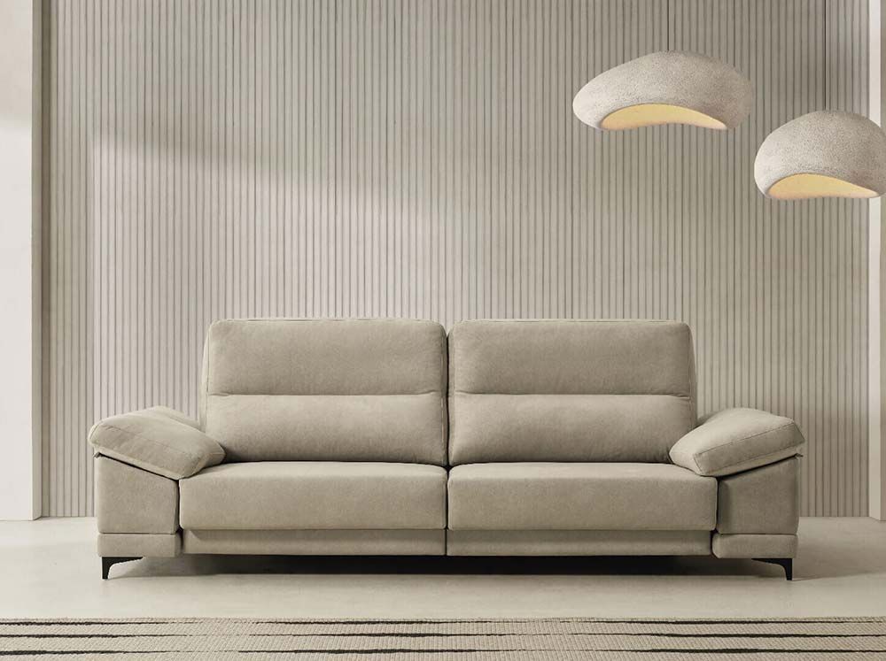 Un sofá beige está sentado en una sala de estar al lado de una lámpara.