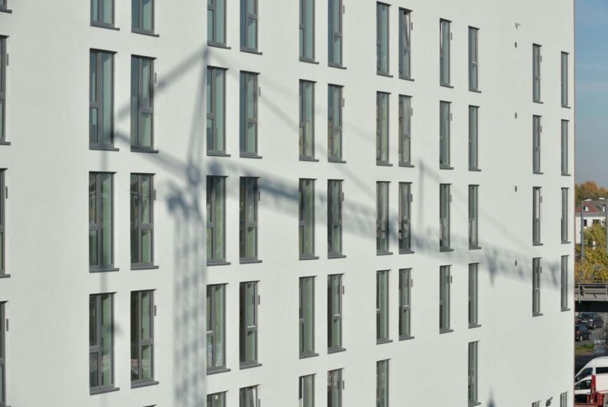 Ein großes weißes Gebäude mit vielen Fenstern und einem Schatten darauf.