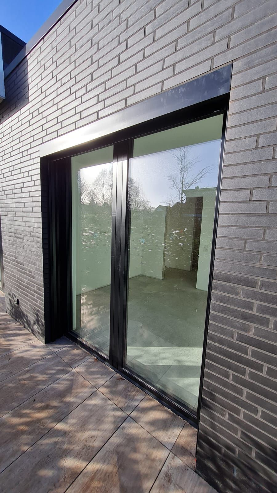Eine große Glasschiebetür an der Seite eines Backsteingebäudes.