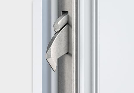 Eine Nahaufnahme eines Türriegels aus Edelstahl an einer weißen Tür.