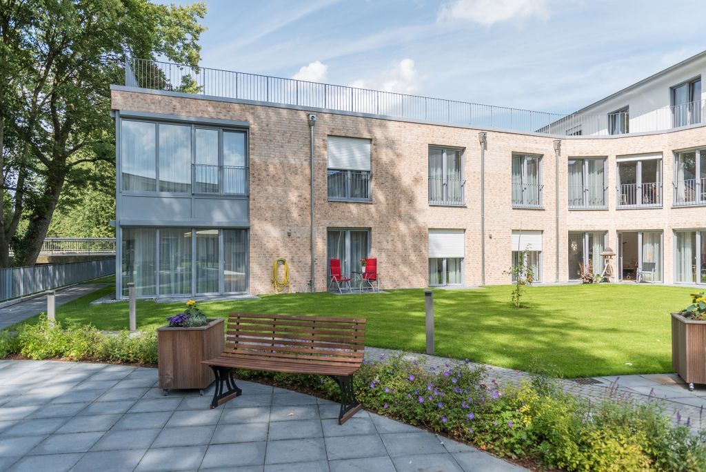 Ein großes Gebäude mit vielen Fenstern und einer Bank davor.