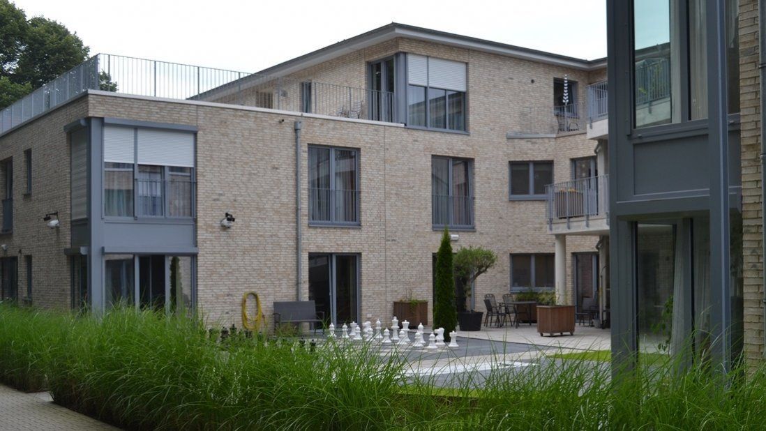 Ein großes Backsteingebäude mit einem Brunnen davor.