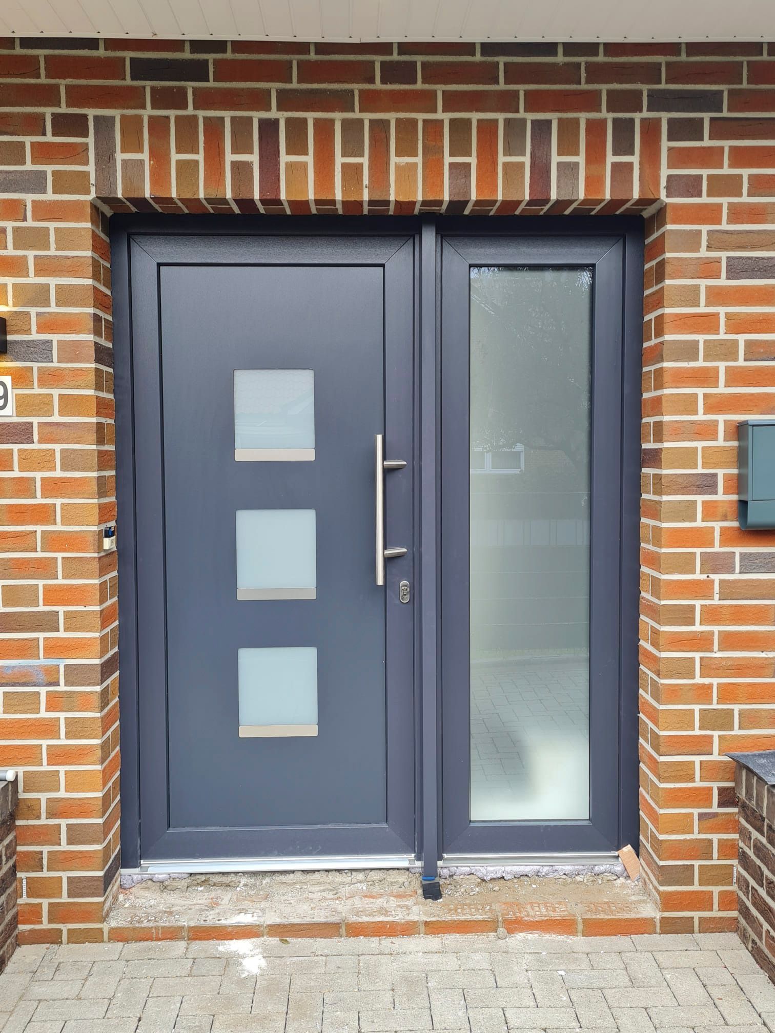 Ein Backsteingebäude mit einer grauen Tür und einem Briefkasten