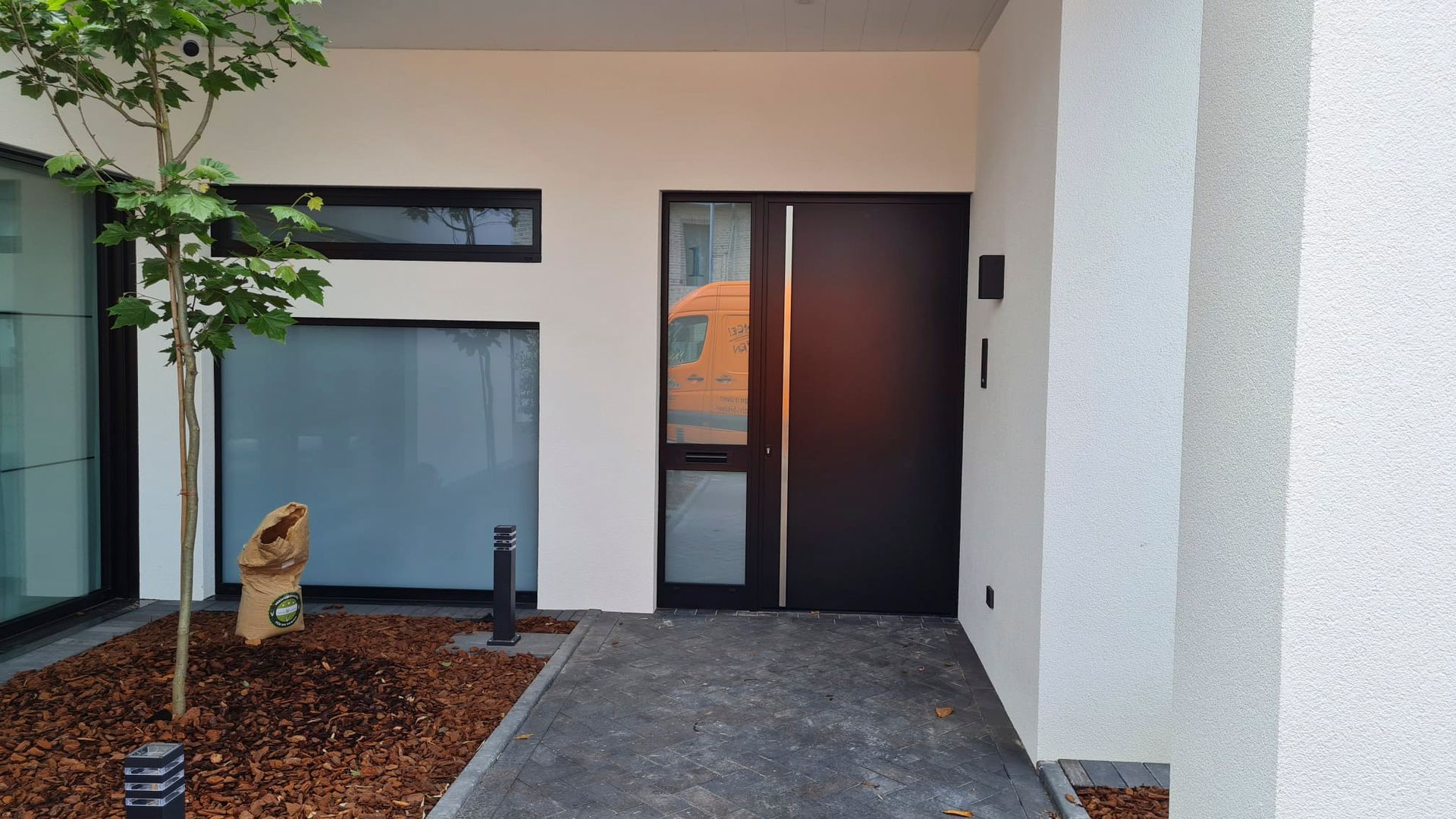Ein weißes Gebäude mit einer schwarzen Tür und einem Baum davor