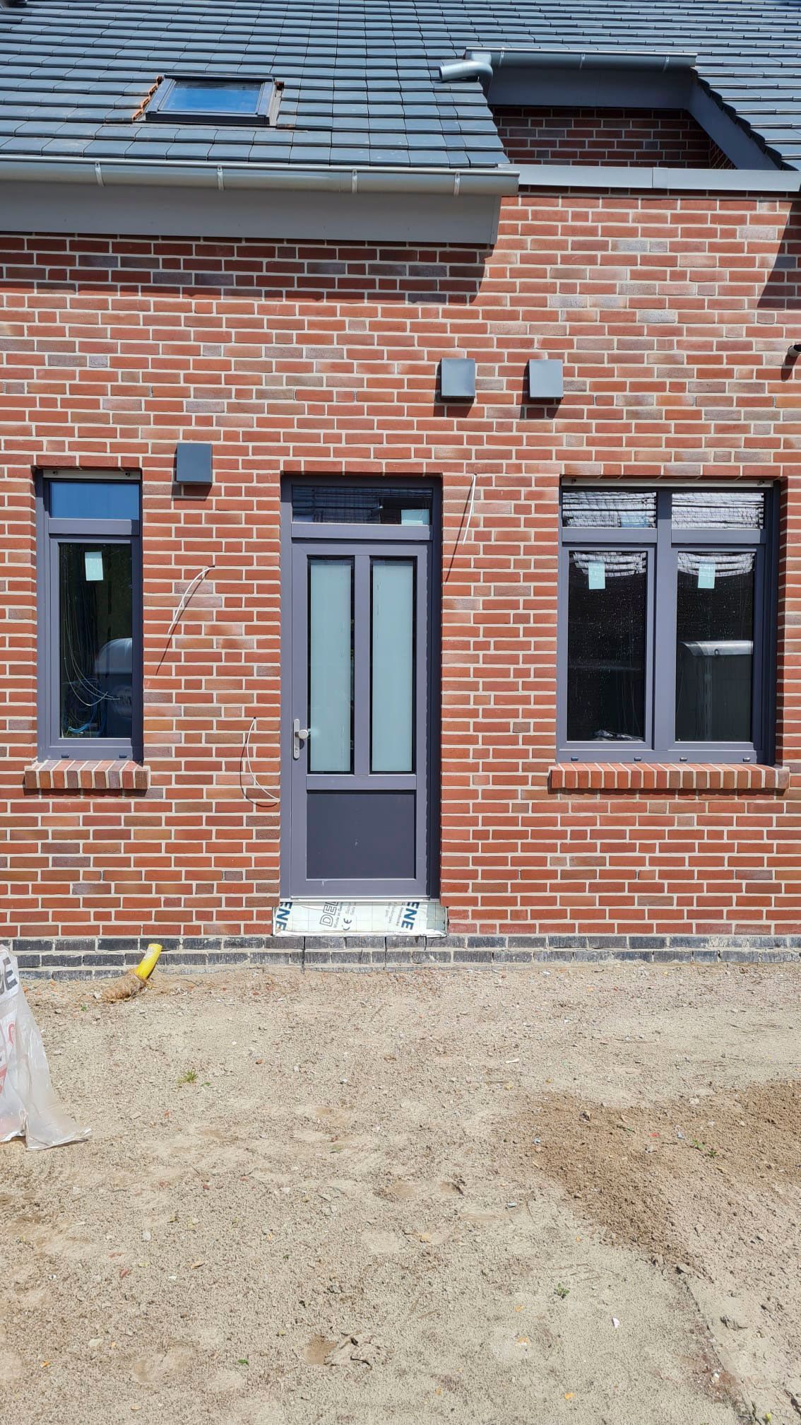 Ein Backsteingebäude mit einer Tür und zwei Fenstern