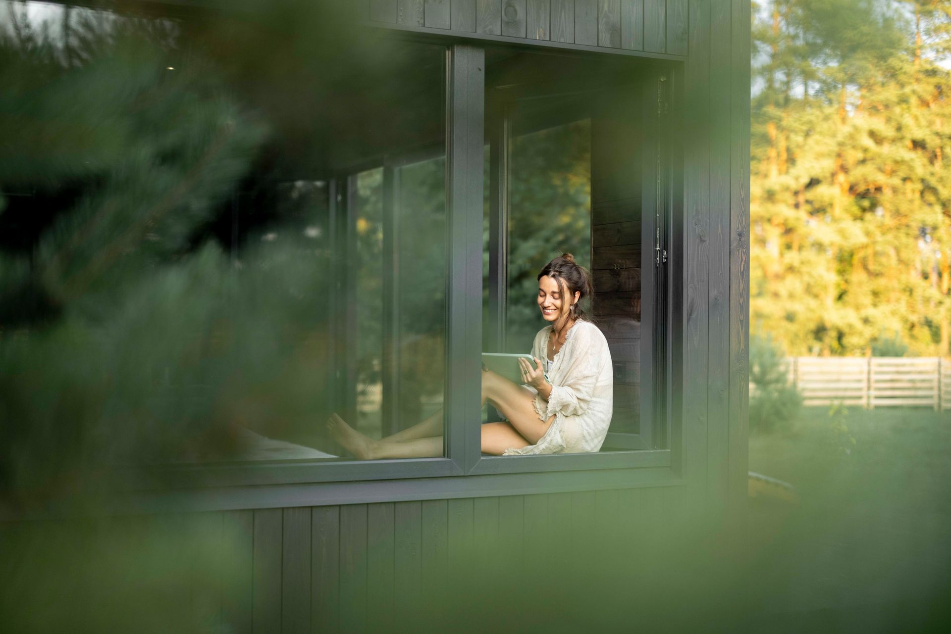 Eine Frau sitzt mit einer Tasse Kaffee in einem Fenster.