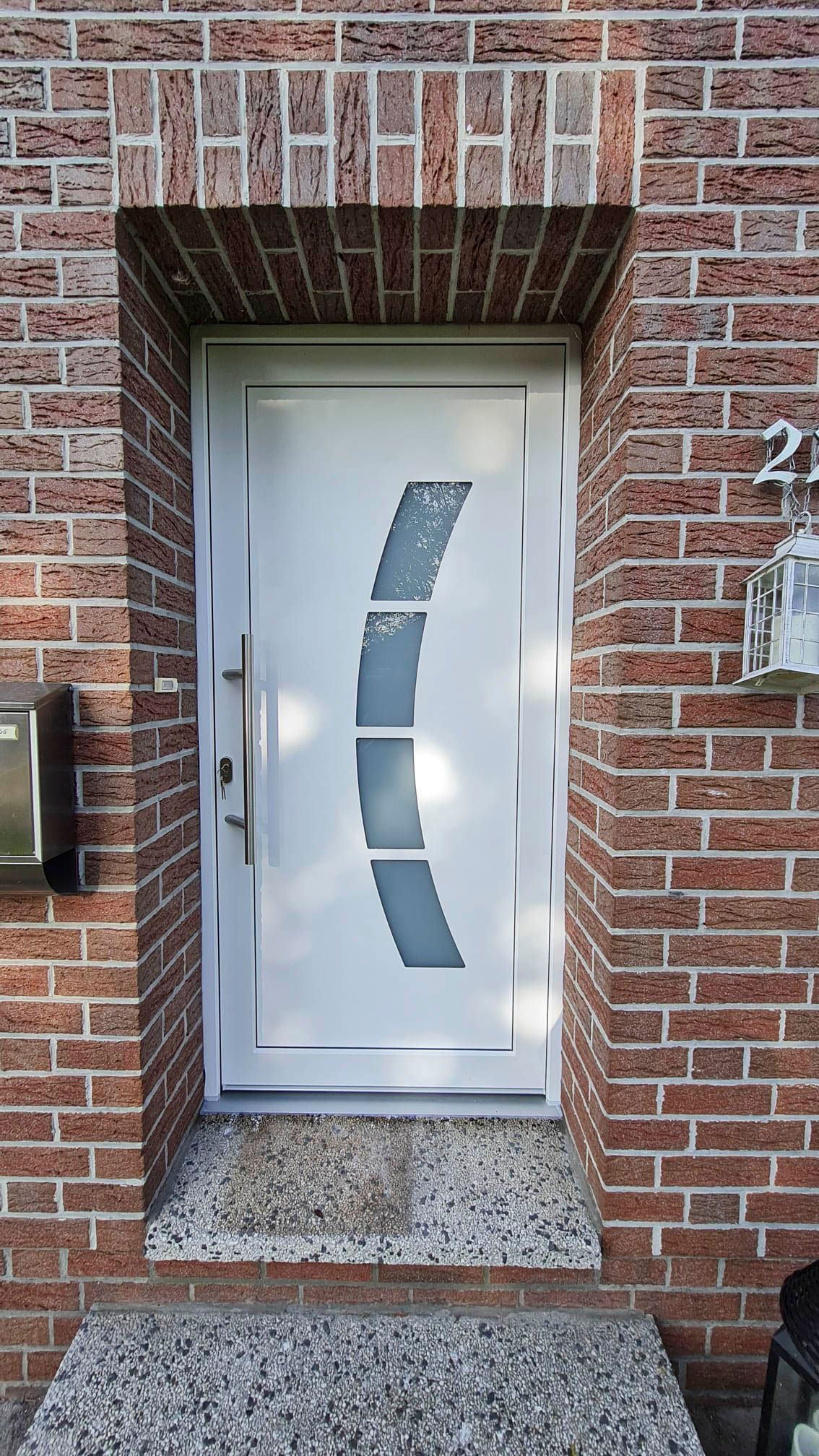 Eine weiße Tür befindet sich an einer Backsteinmauer neben einem Briefkasten.
