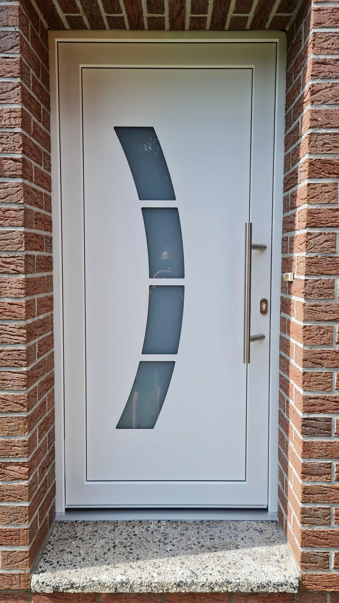 In einer Backsteinmauer steht eine weiße Tür.