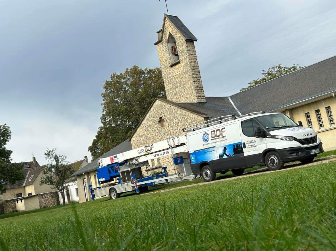 Camions de l'entreprise B.D.F. sur le chantier d'une bâtisse avec un clocher