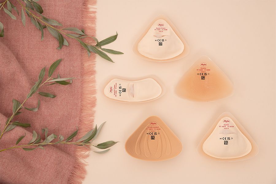 Persona corriendo con una pierna protésica; al aire libre en un sendero entre arbustos; pantalones rosas, zapatos rojos y blancos.