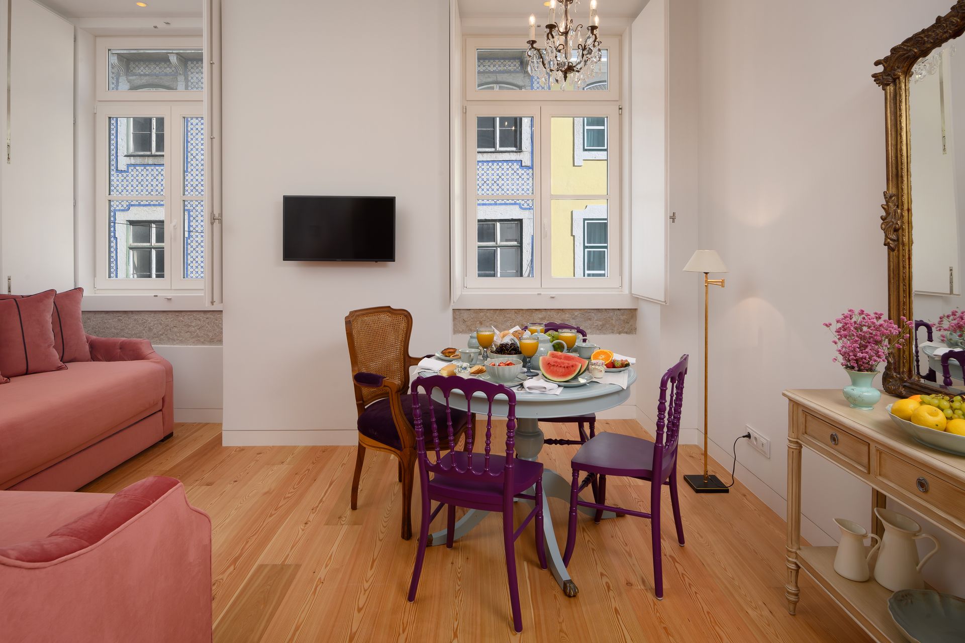 Living room with dining table set for breakfast and a pink sofa.