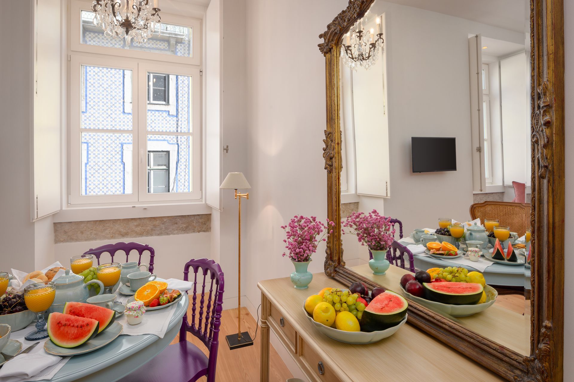 Dining room with table set for breakfast; fruit platter on console table. Mirror reflects the breakfast setup.