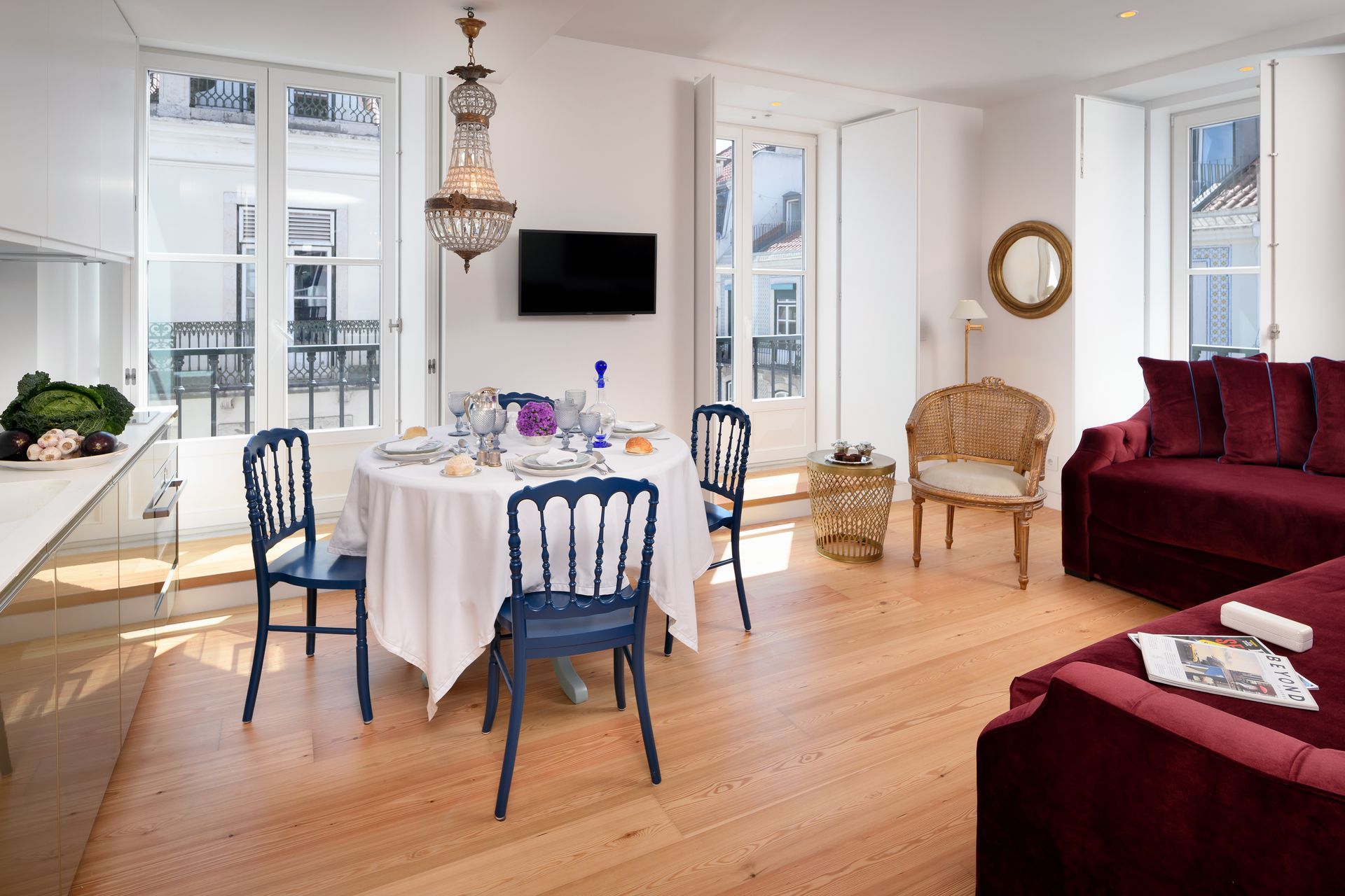 Living room with dining table, blue chairs, red sofa, and large windows.