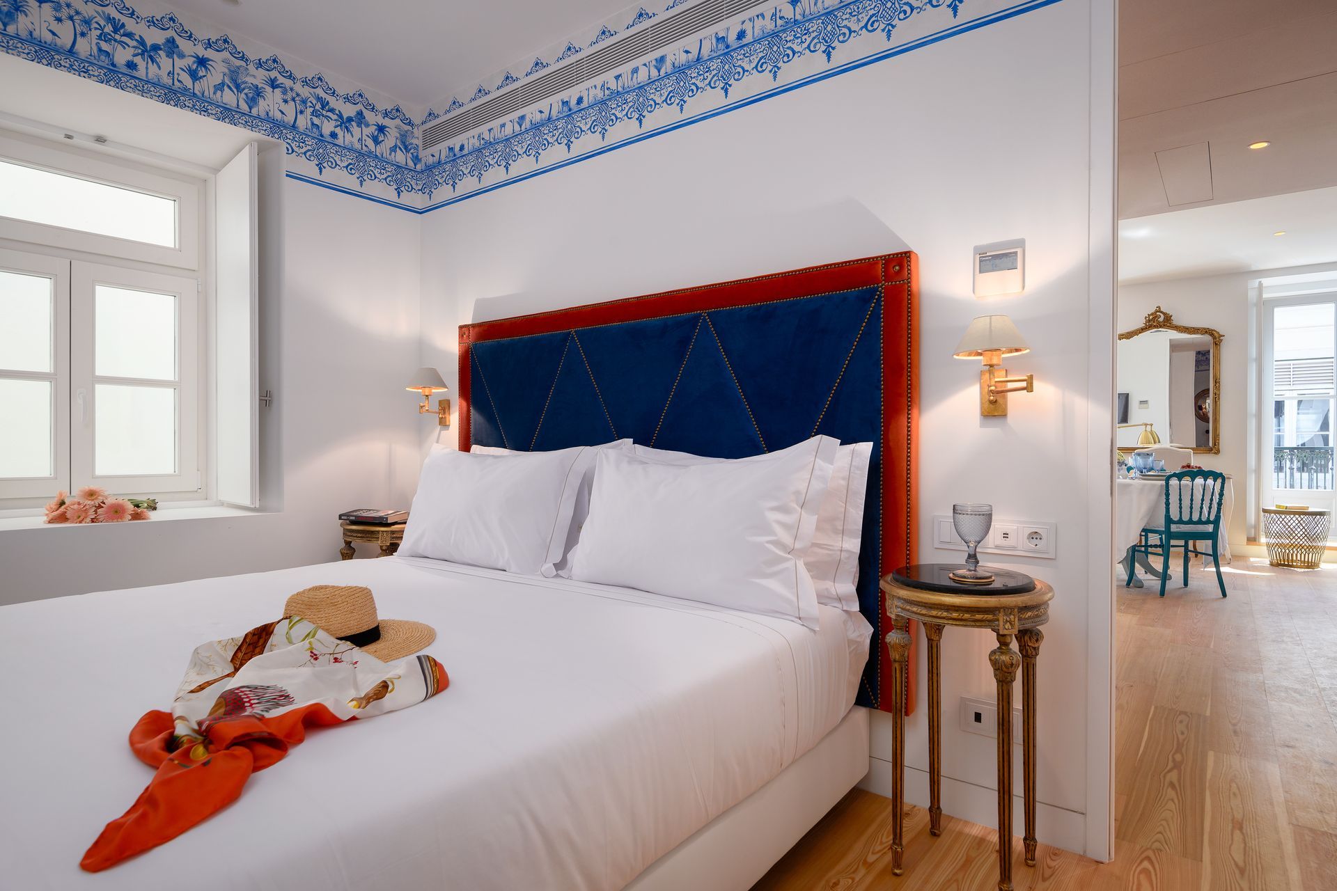 Bedroom with a blue headboard, white bedding, and a decorative blue and white painted ceiling trim.