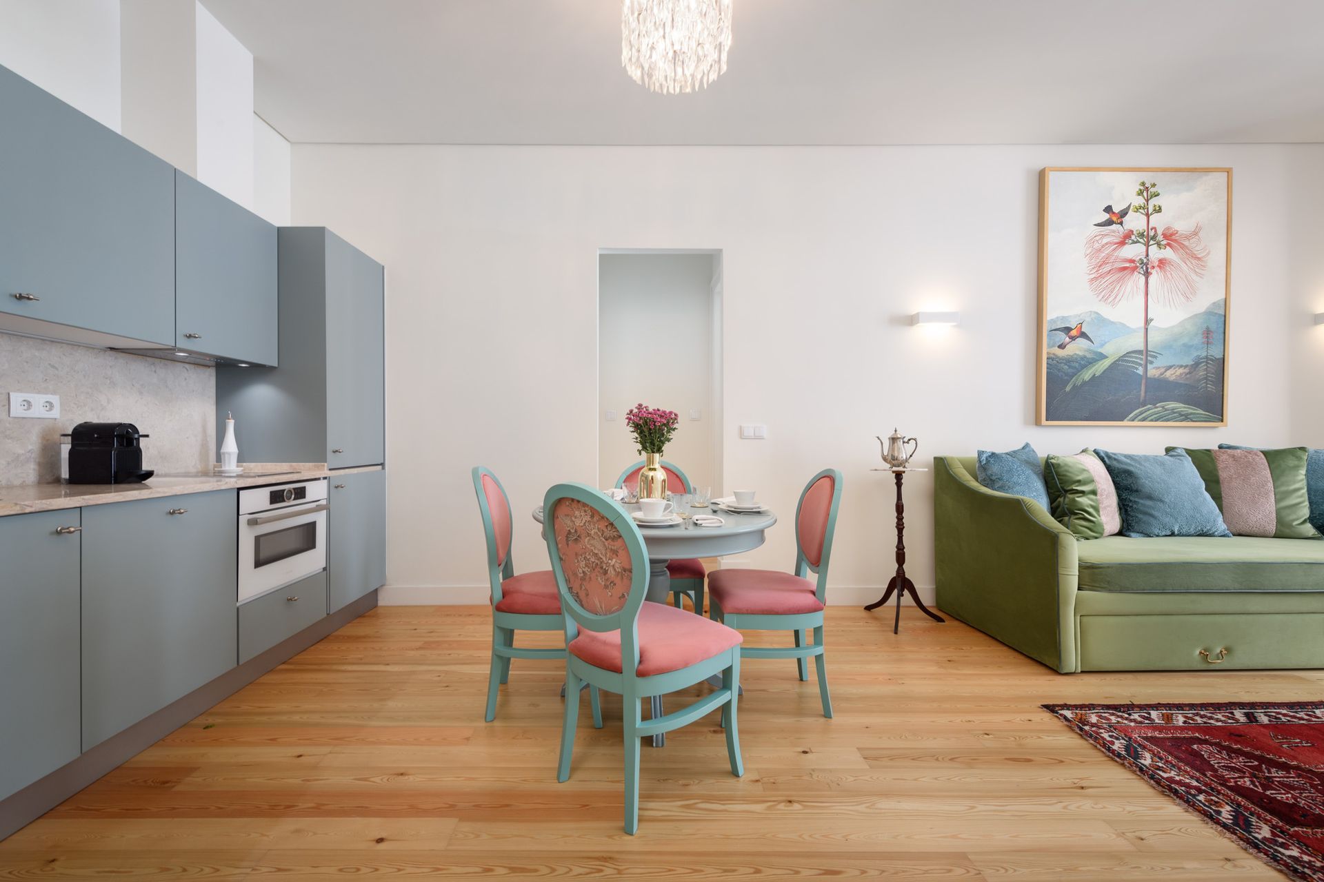 Modern apartment interior with kitchen, dining area, and living room featuring light wood floors and blue accents.