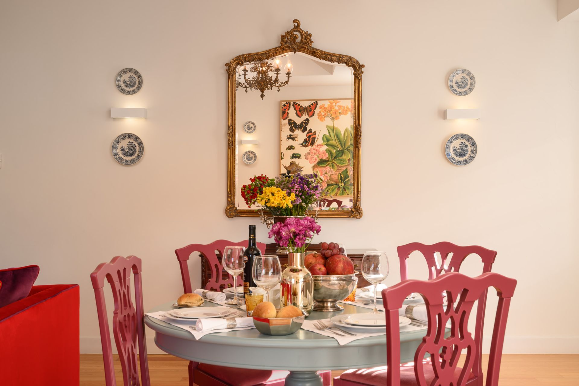 Dining room: a round blue table set for four, with fuchsia chairs and a large antique mirror.