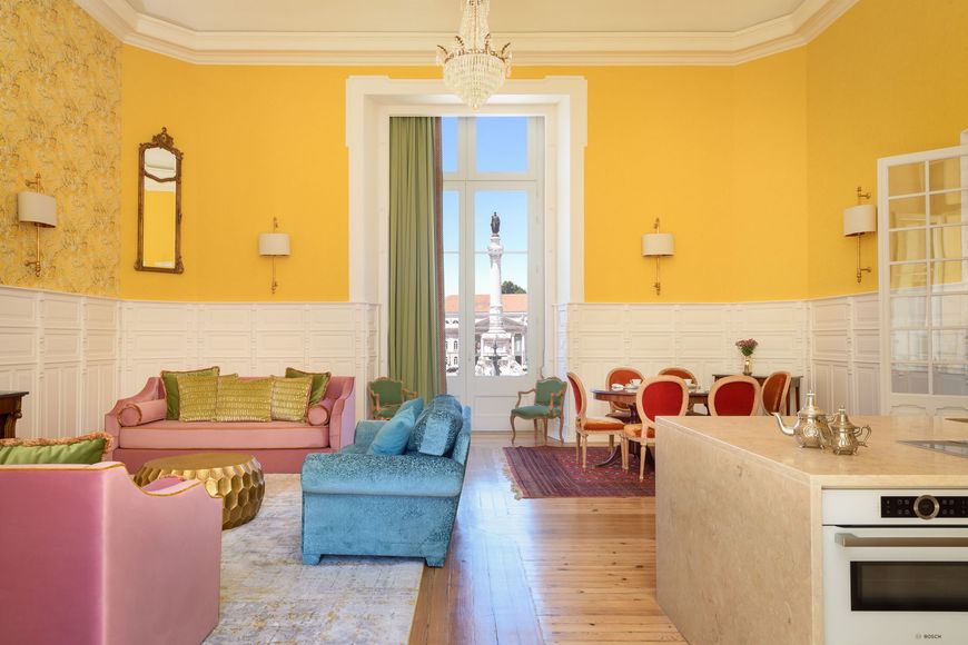 Spacious room with yellow walls, pastel furniture, a rug, and a large window.