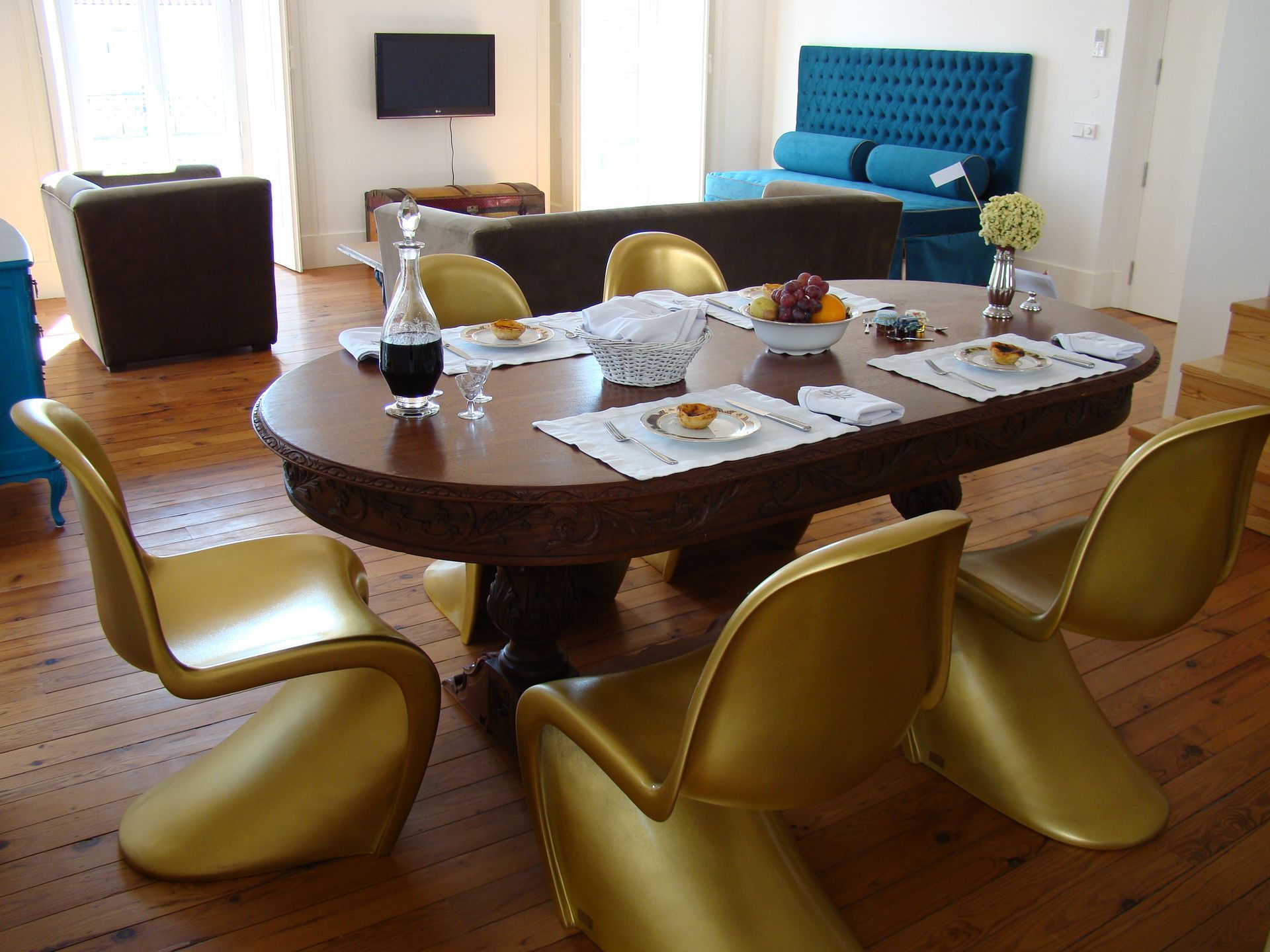 Dining area with modern wooden table and stylish golden chairs in a duplex two-bedroom apartment.