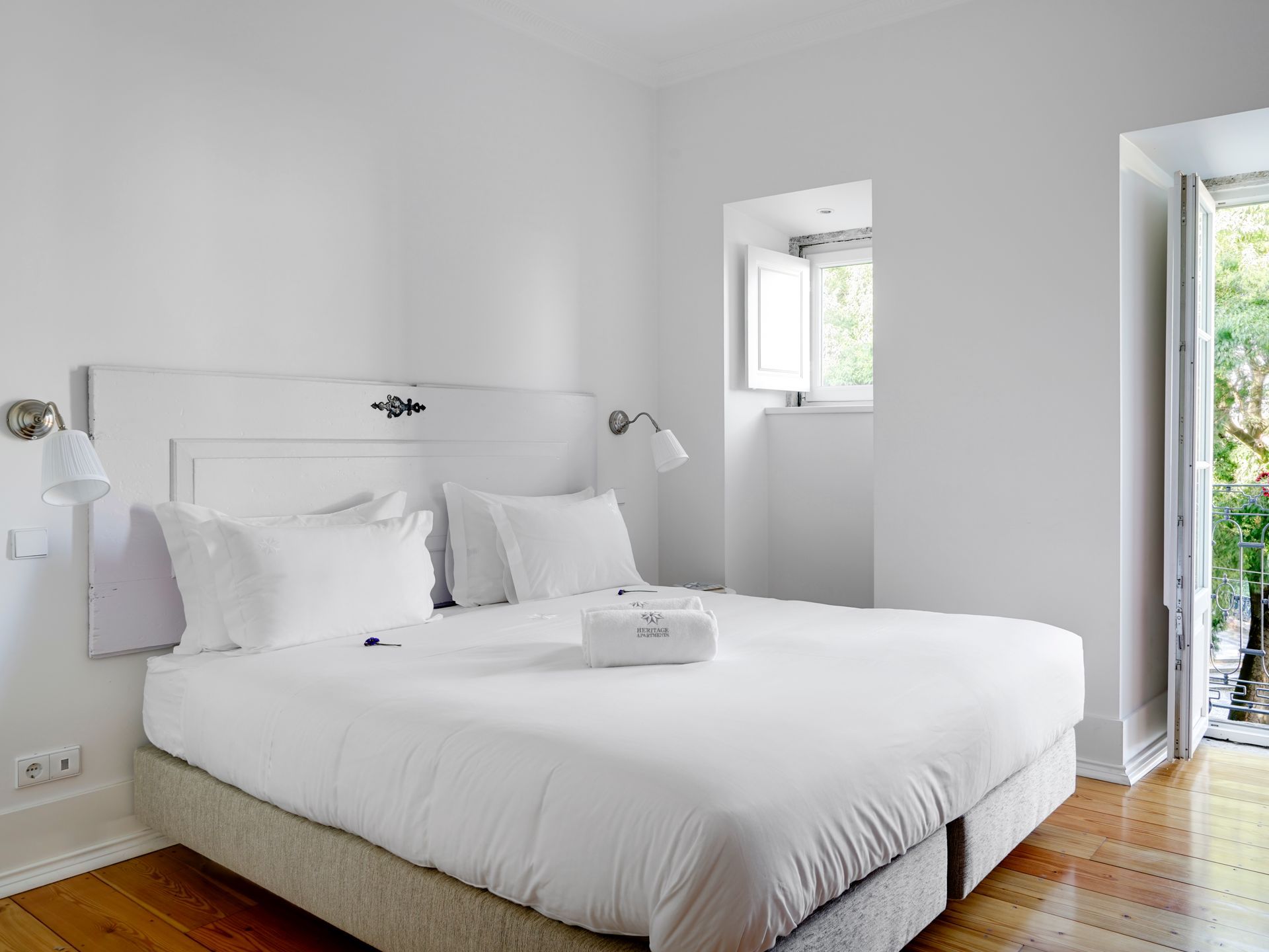 Bright bedroom with white decor and natural light in a spa deluxe two-bedroom apartment.
