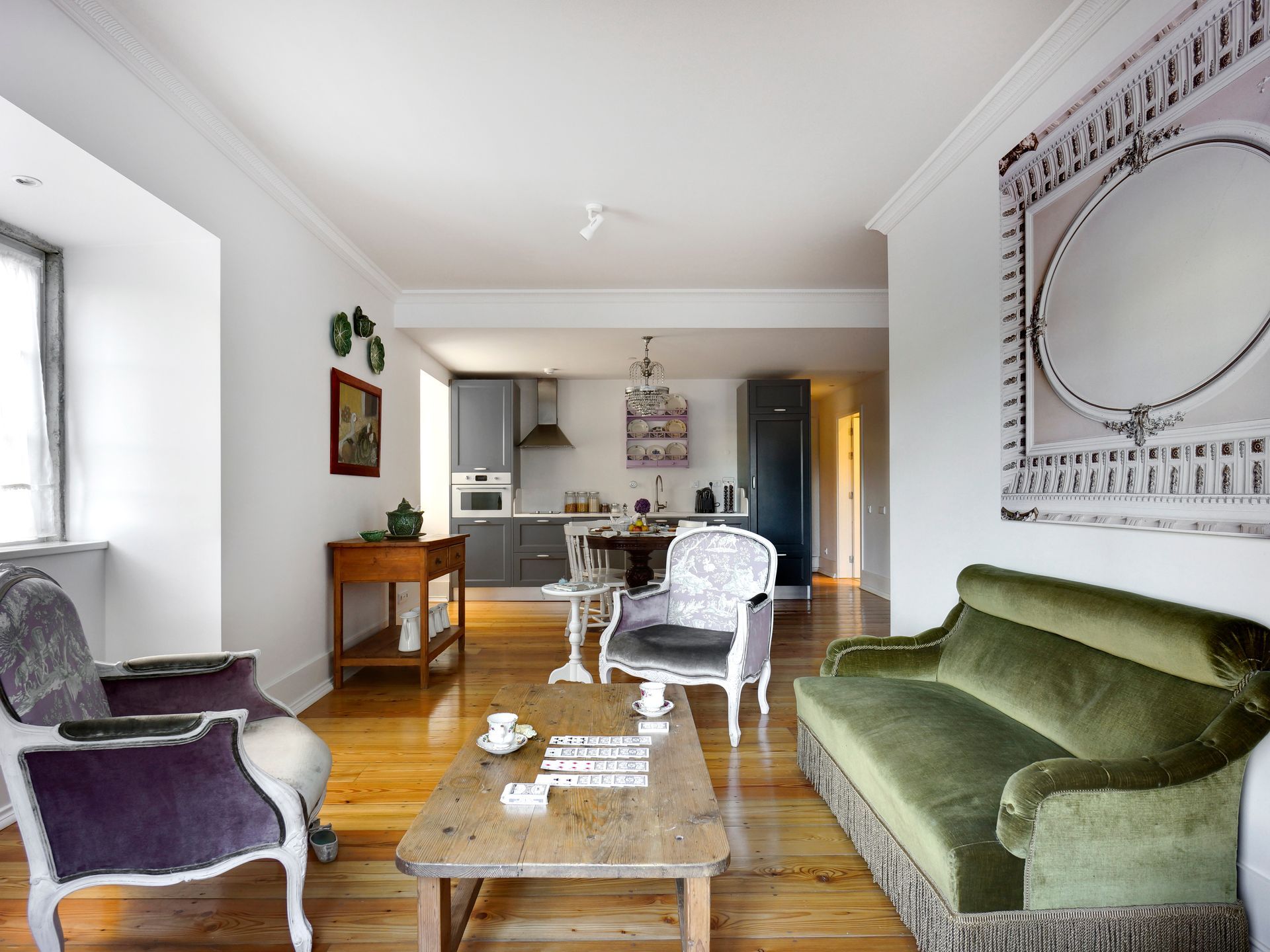 Open-plan living and kitchen area with green seating and modern appliances in a deluxe two-bedroom apartment.