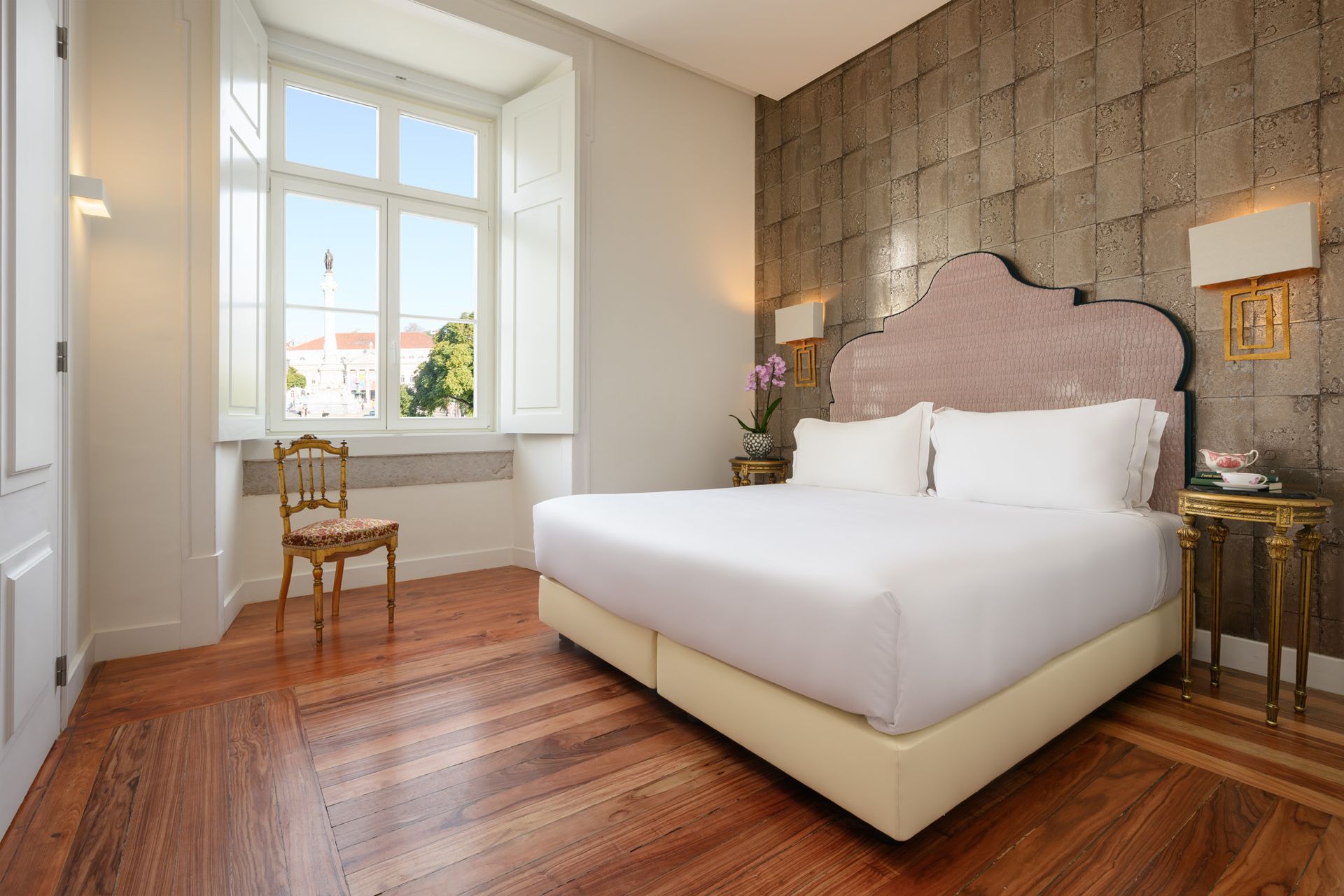 Hotel room with a large bed, wooden floor, and window overlooking a street.