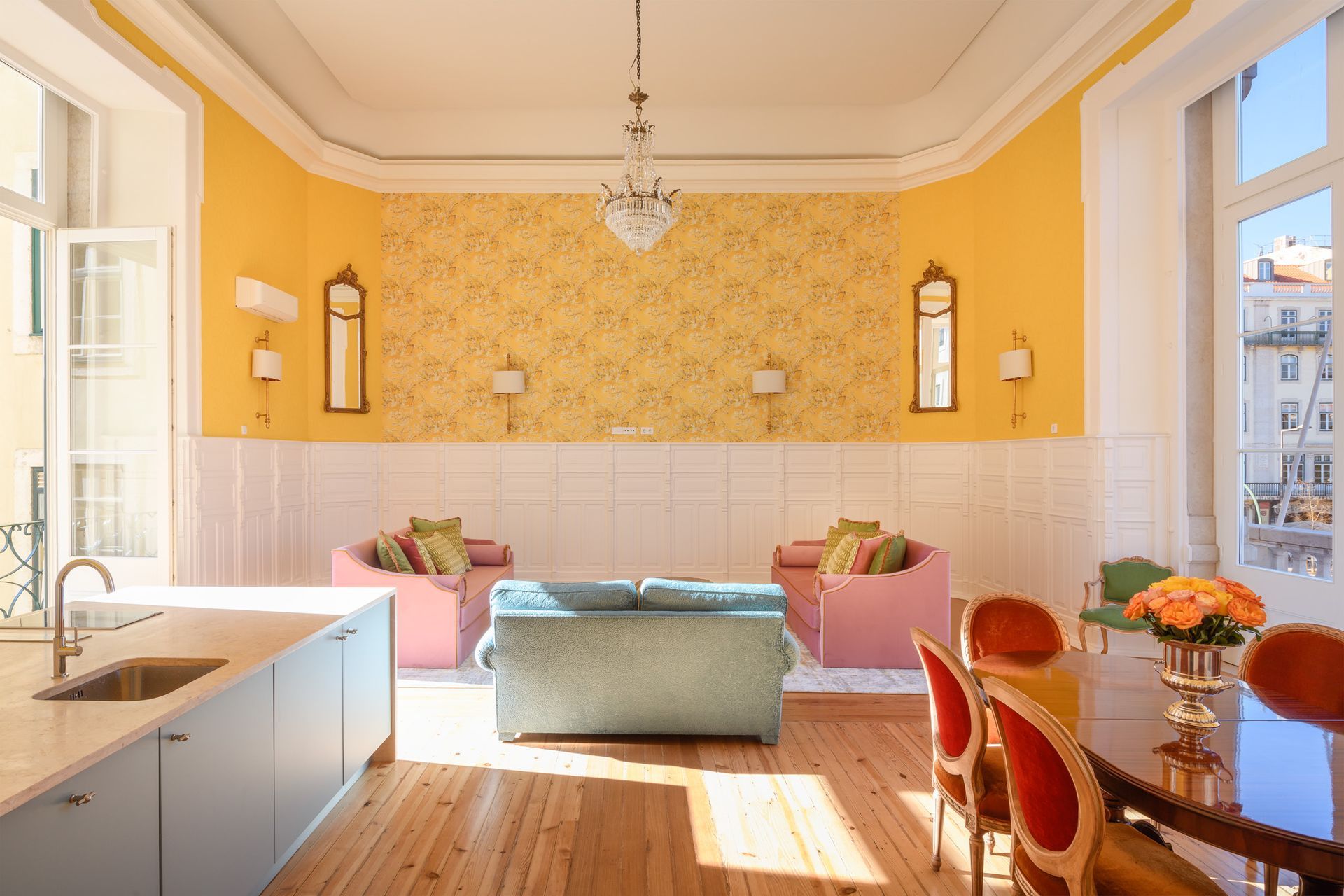 Living room with yellow walls, floral wallpaper, colorful seating, and a dining table.