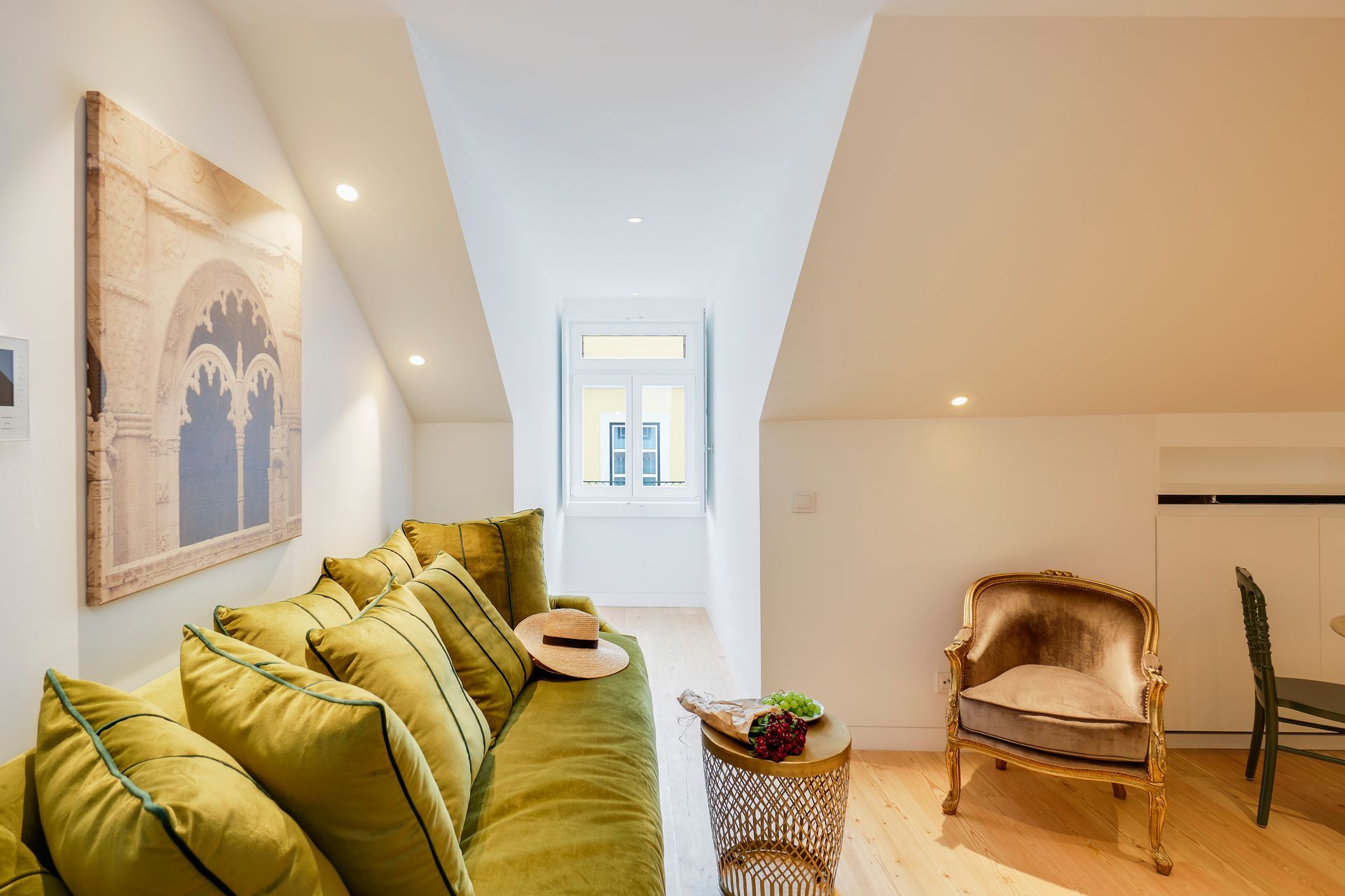Cozy living room with green sofa, ornate chair, and a view to a window.