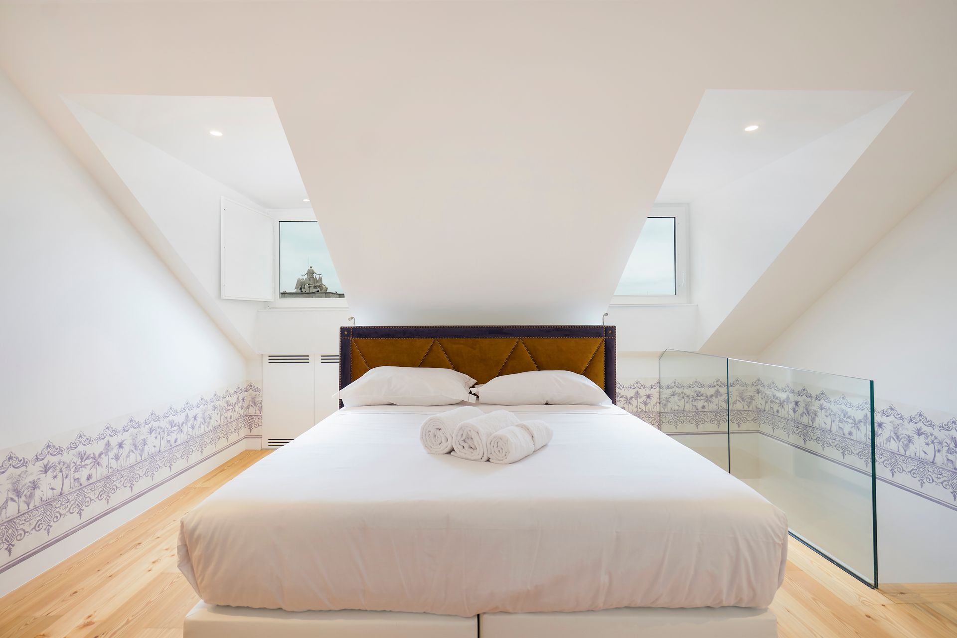 White bedroom with bed, angled ceiling, and decorative wall border.