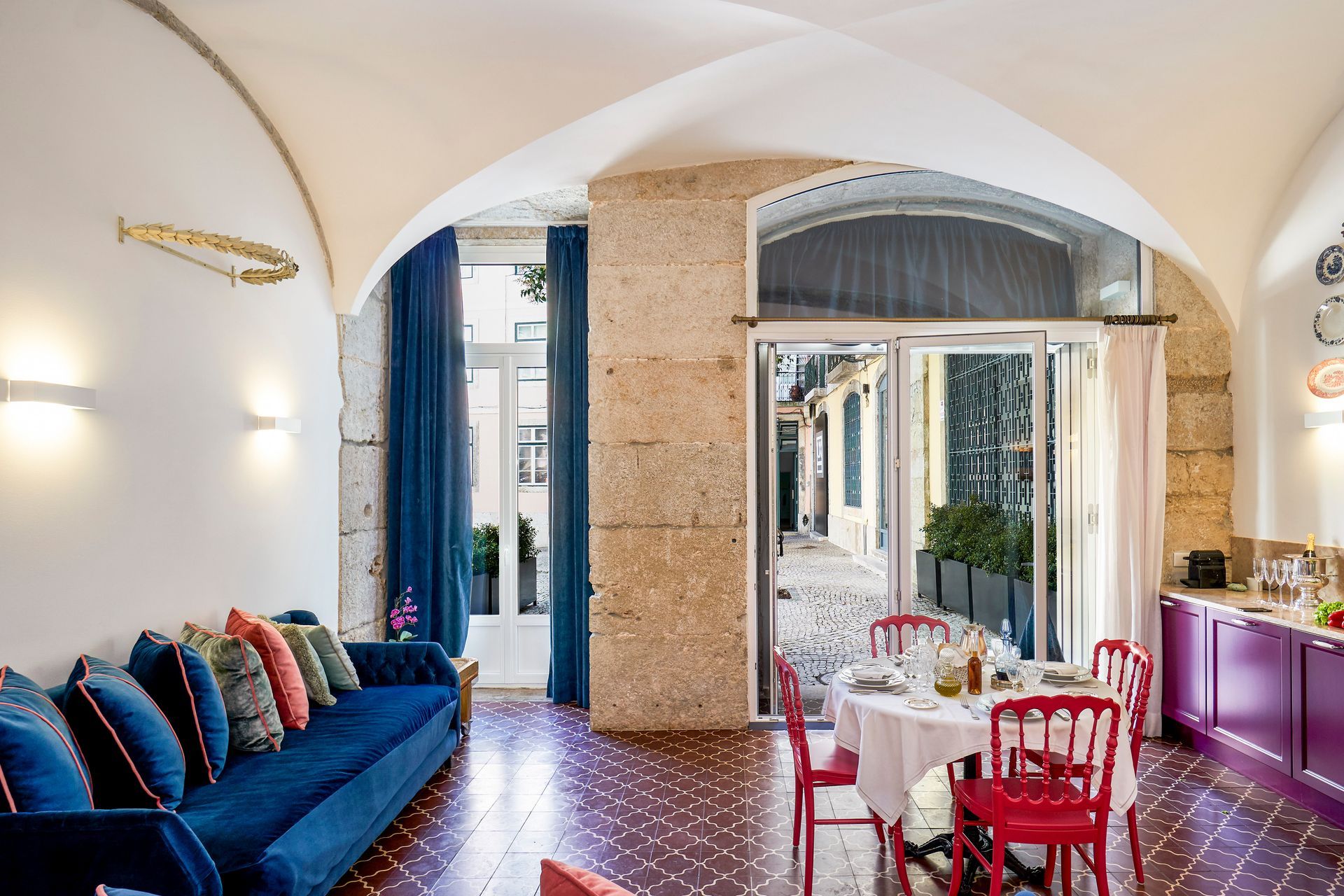 Living room with a blue couch, red chairs, and a view of a cobblestone street.