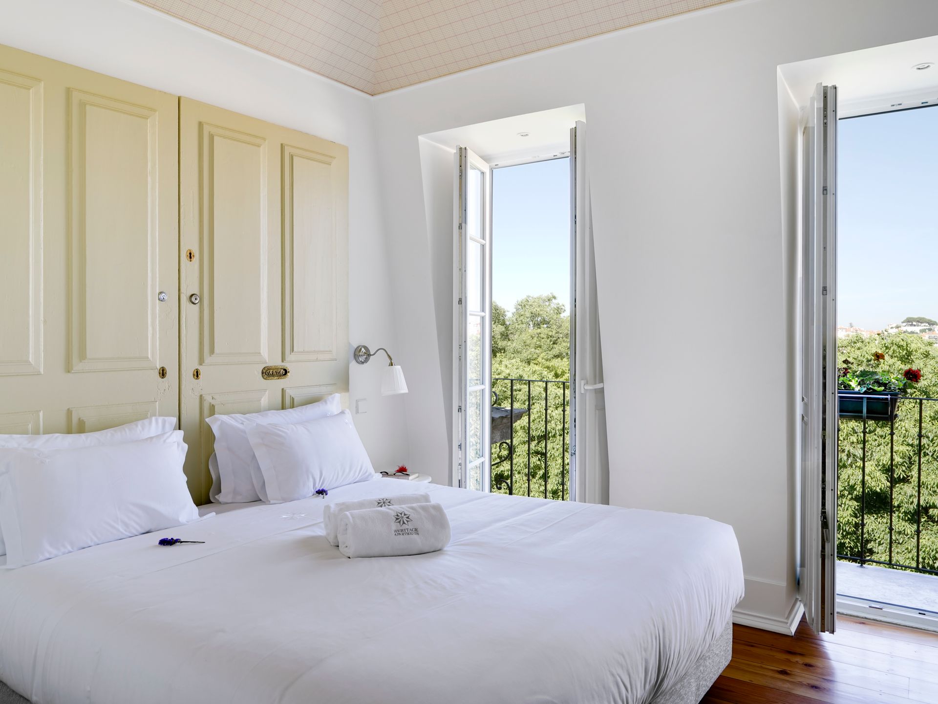 Elegant bedroom with light decor and a balcony view in a spa penthouse two-bedroom apartment.