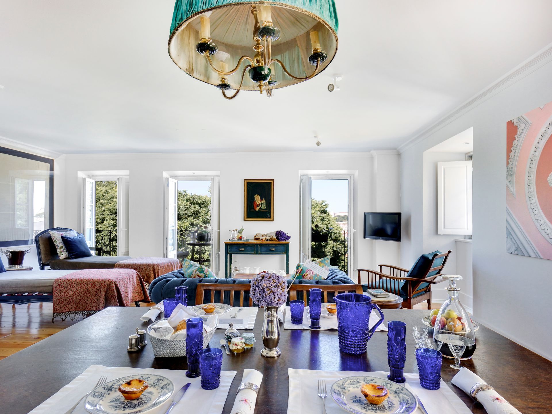 Stylish living room in a premium one-bedroom apartment with a dining table, colorful decor, and natural light.