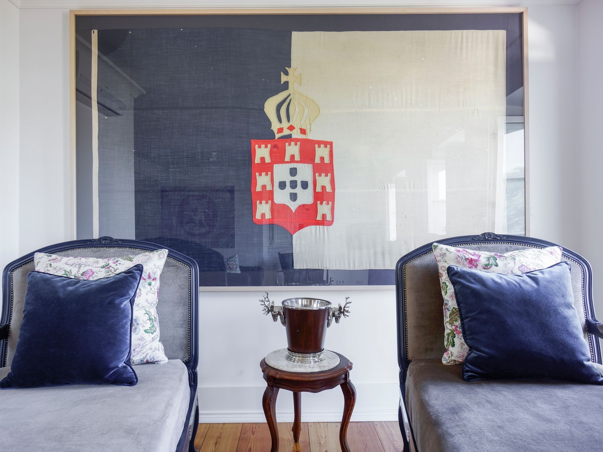 Stylish bed area in a spa premium one-bedroom apartment with a large Portuguese coat of arms painting.