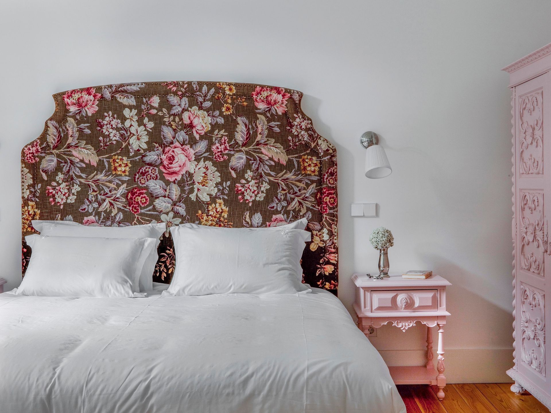 Romantic bedroom in a deluxe one-bedroom apartment with floral headboard and pastel pink decor.