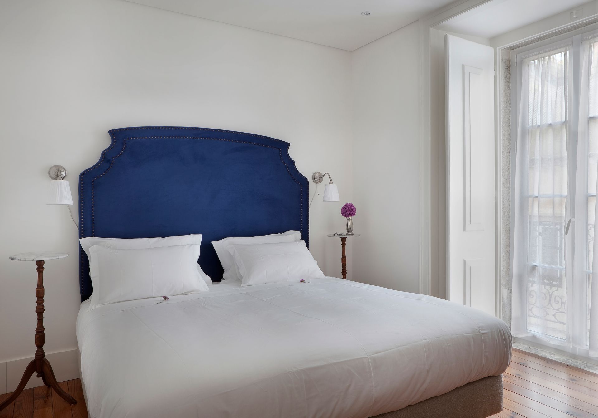 Bedroom with a blue velvet headboard and natural light in a duplex two-bedroom apartment.