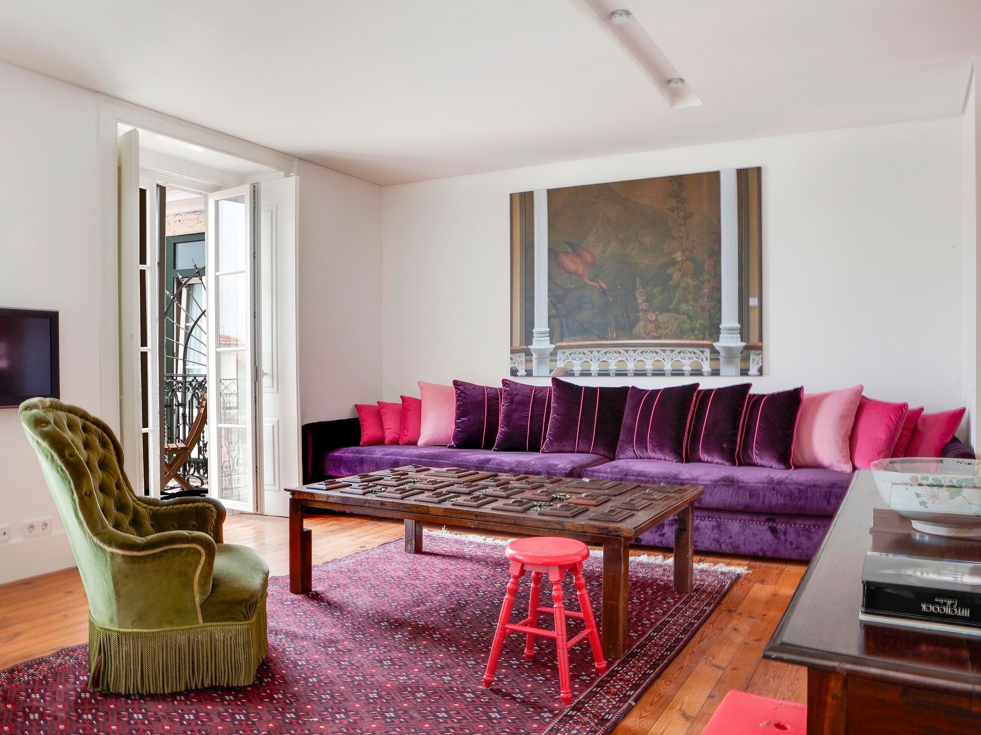 Colorful living room in a duplex one-bedroom apartment with a large purple sofa and bright decor.