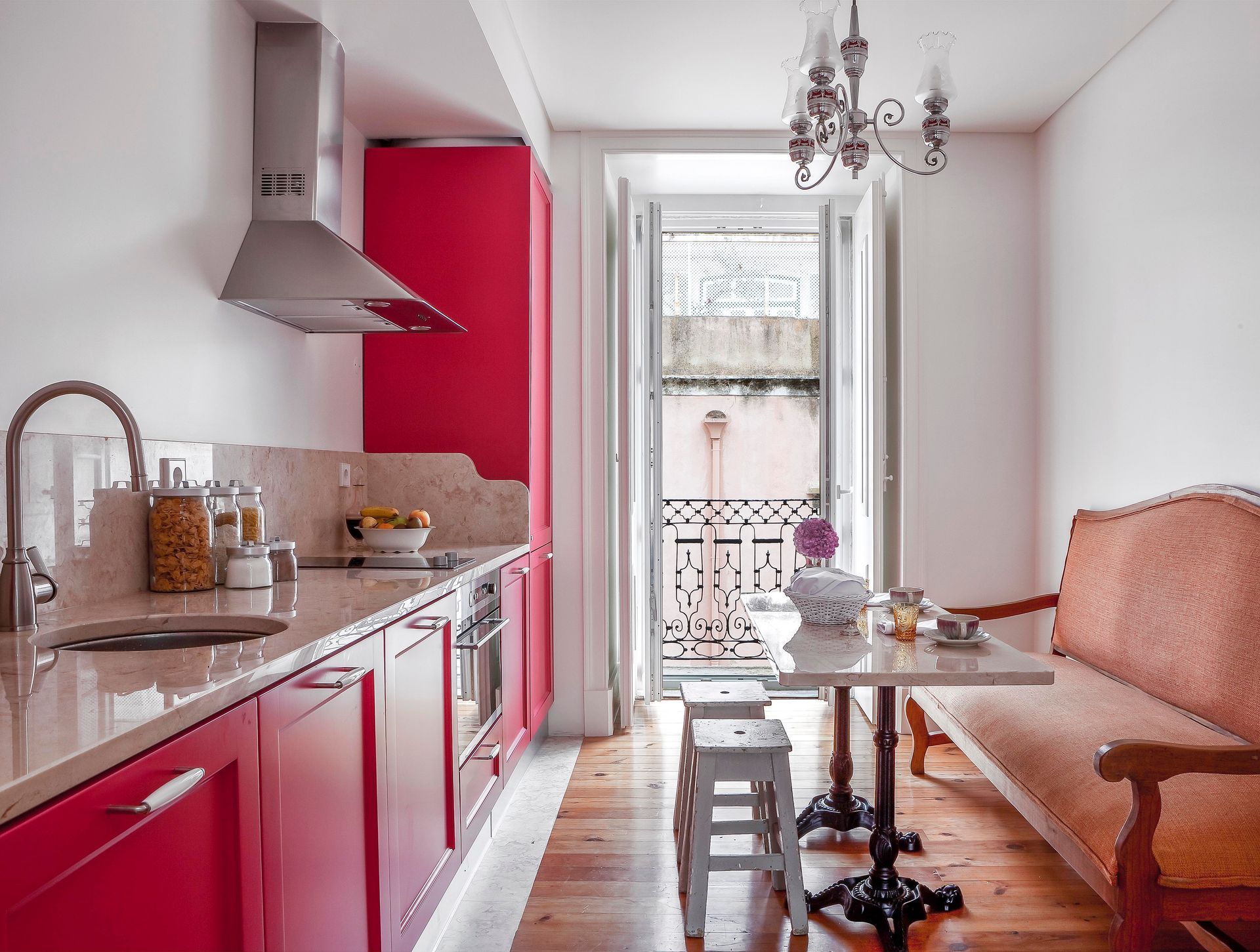 Modern kitchen with red cabinets, stainless steel appliances, and a chandelier in a duplex one-bedroom apartment.