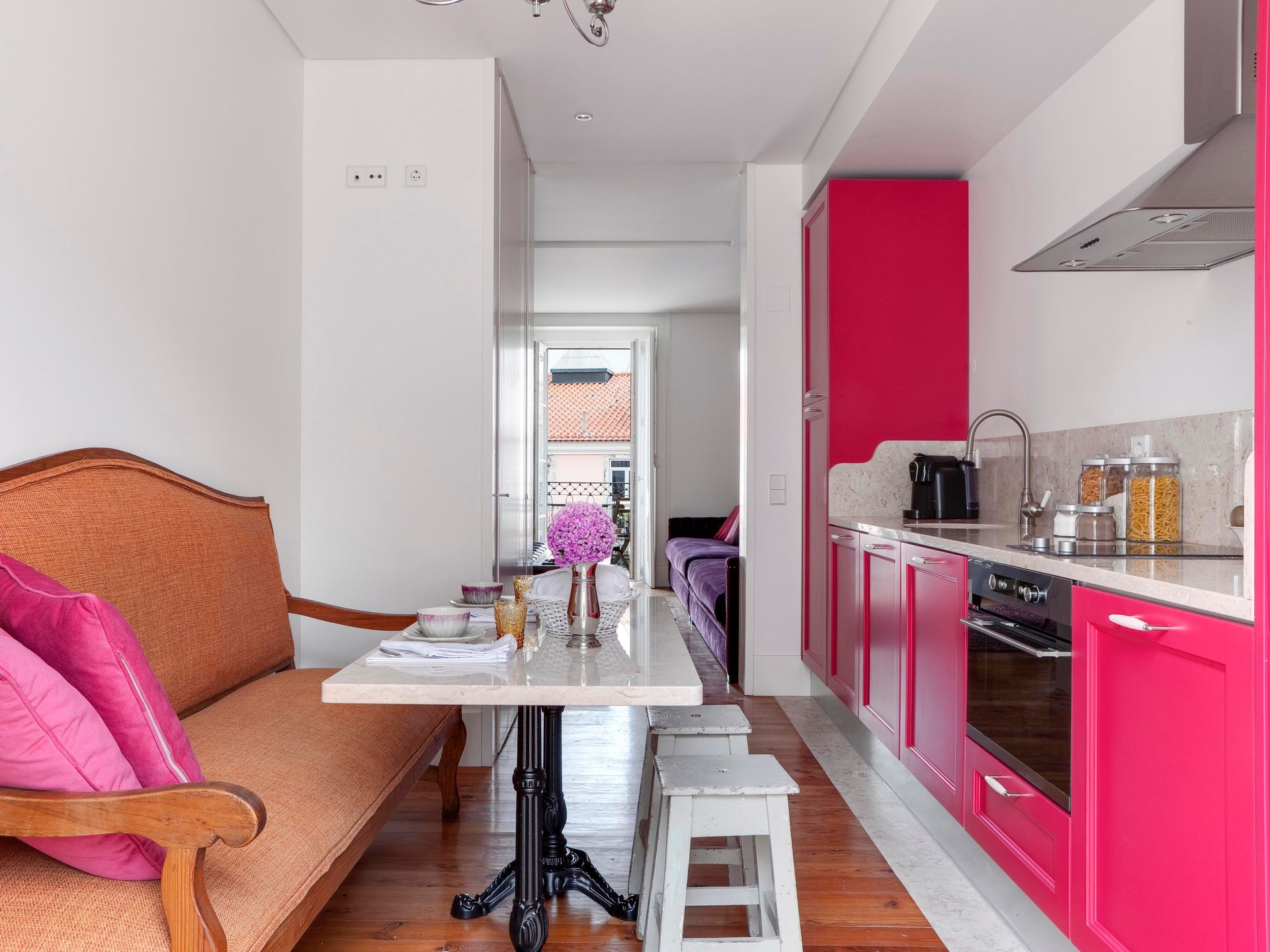 Modern kitchen with pink cabinets and dining table in a duplex one-bedroom apartment.