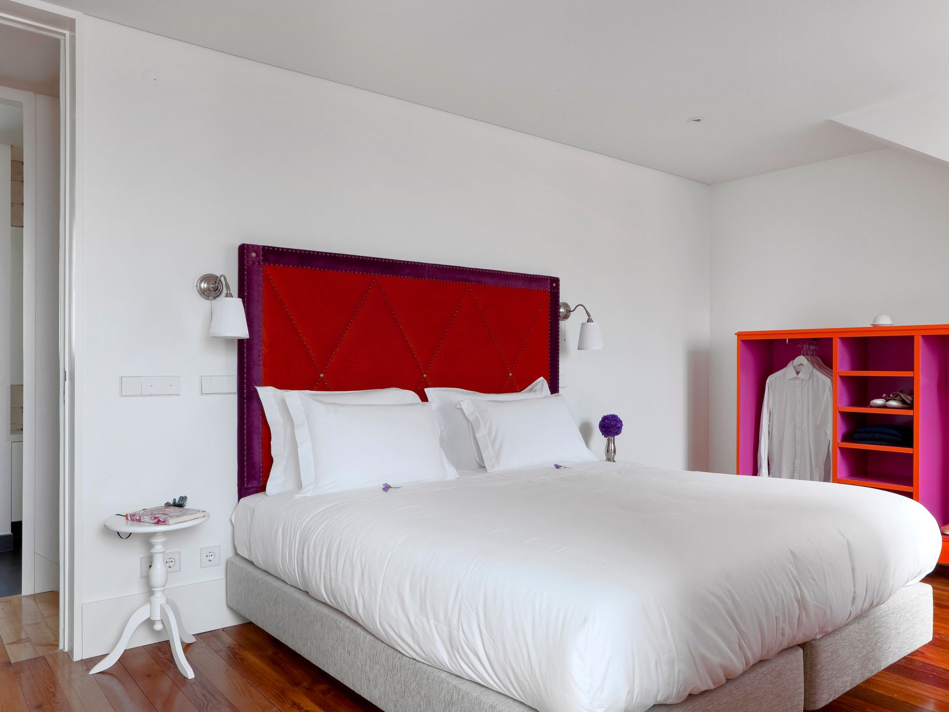 Vibrant bedroom with red headboard and colorful furniture in a duplex one-bedroom apartment.