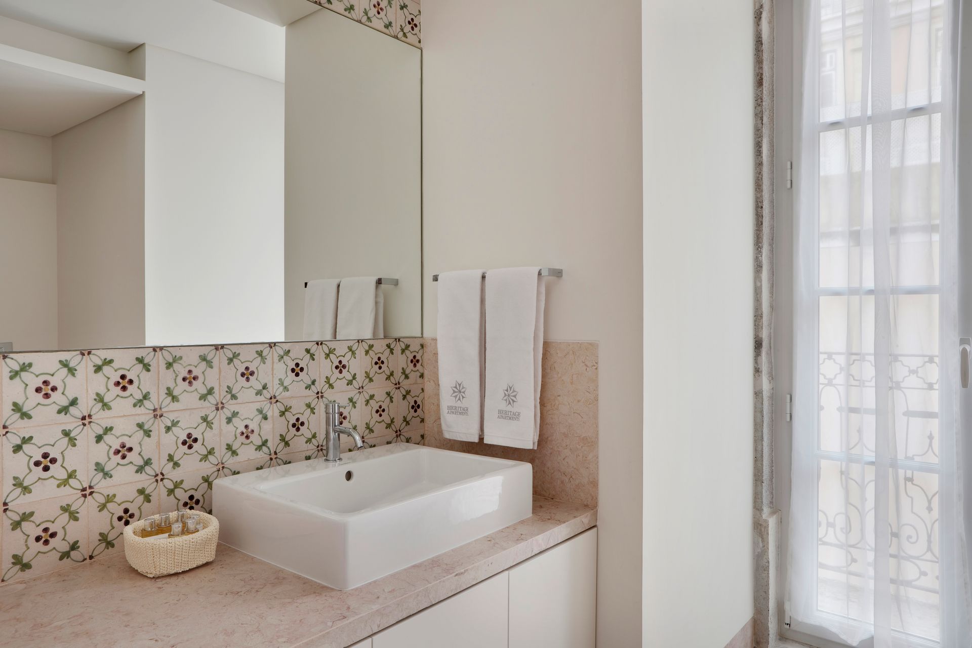 Modern bathroom with floral wall tiles, sink, and towels in a duplex two-bedroom apartment.