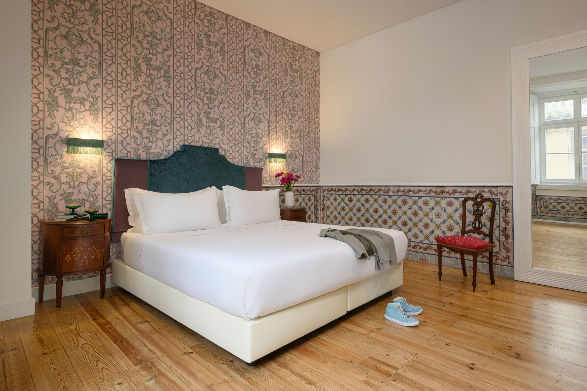 Bedroom with a large bed, patterned wallpaper, wooden floor, and decorative tiling.
